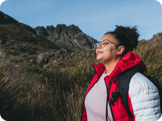 Woman smiling while hiking with mountains around her.