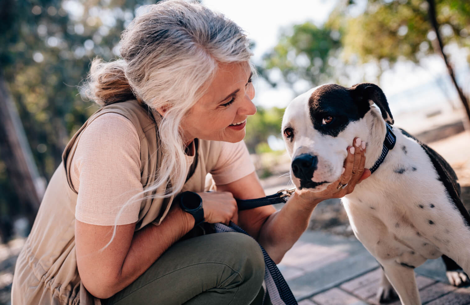 Woman crouching while smiling at and petting her dog